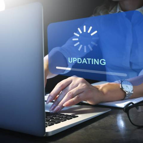 A woman wearing a white shirt and a silver watch types on a laptop. A floating graphic displays a loading bar icon.